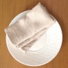 Serviette de table grège et écologique en lin naturel dans une assiette blanche